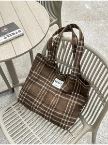 Brown plaid tote with matching handles and a white front label, displayed on an outdoor chair