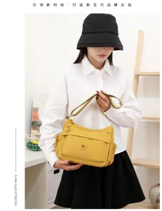 Una donna tiene una borsa gialla in nylon, con tasca frontale zip e badge rotondo in metallo