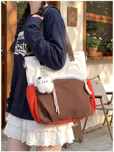 Vue en situation d’un sac en toile multicolore avec pompon en peluche, porté devant un café