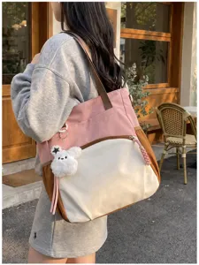 Femme portant dehors un cabas rose et crème à bordure brune, avec un porte-clés lapin tout doux
