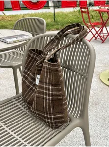 Brown plaid tote with double handles displayed on a gray outdoor chair, showing its woven texture