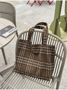 Brown plaid tote with twin handles on a gray chair, showing textured fabric and an open top