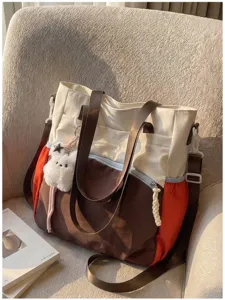 Sac cabas coloré sur un canapé, anses brunes, côtés orange et breloque étoile en peluche