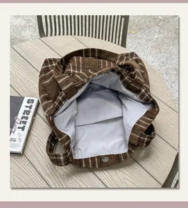 Top-down view of an open brown plaid bag showing its gray lining and metal snap closure