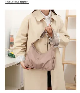 Sac en nylon rose poudré, froncé sur les côtés, porté avec une large bandoulière tissée