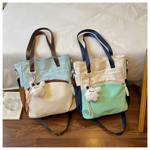 Deux sacs bicolores avec oursons en peluche, bandoulières et poches latérales, présentés côte à côte