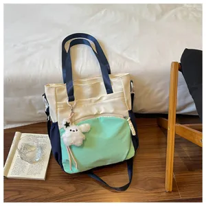 Sac avec poche menthe, anses bleu marine et ourson en peluche, posé près de livres ouverts