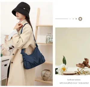 Sac bleu marine froncé porté en bandoulière, avec détail de bouton et décor floral doux