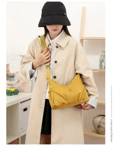 Modèle portant un sac jaune en nylon, à corps froncé et large bandoulière tissée assortie