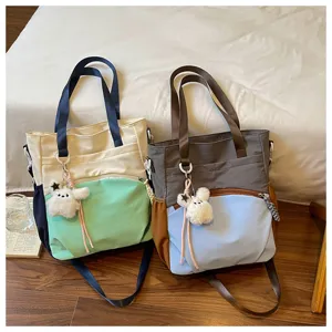 Deux sacs bicolores avec pendentifs ourson en peluche, côte à côte sur le lit près du parquet