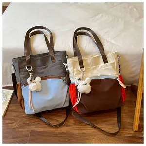 Deux sacs bicolores côte à côte, avec des anses brunes et des breloques lapin toutes douces