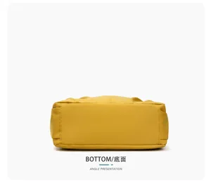 Vue du dessous d’un sac bandoulière jaune en tissu, avec une base plate et des coutures froncées