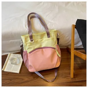 Vue rapprochée du sac jaune et rose, avec poche avant zippée incurvée et longues anses contrastées