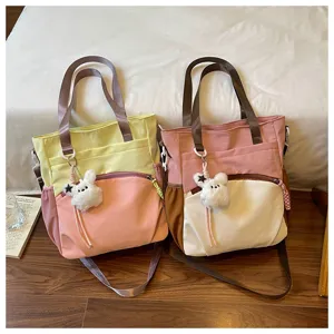 Deux sacs bicolores côte à côte, avec des anses brunes et des breloques lapin en peluche