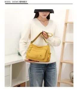 Modèle présentant un sac jaune à plusieurs poches, avec bandoulière et poche latérale à cordon
