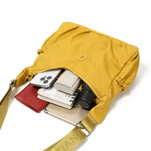 Sac bandoulière jaune en nylon, à ouverture froncée et large sangle, présenté ouvert vu de dessus
