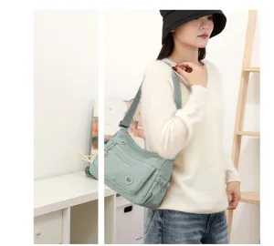 Une femme porte à l’intérieur un sac vert clair à plusieurs poches avant et à large bandoulière