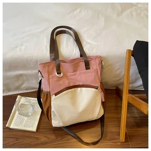 Vue du sac rose et crème avec poignées brunes, poche zippée à l'avant et bandoulière
