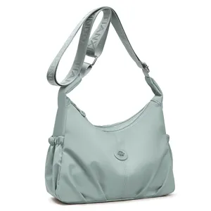 Sac à bandoulière en nylon vert-gris clair, corps froncé, sangle réglable et ornement rond en métal
