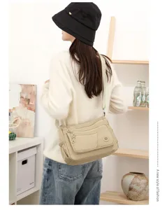 Vue de dos d’un modèle portant un sac beige à poches zippées superposées et sangle réglable