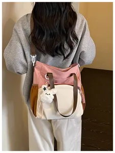 Vue de dos d’une femme portant un sac rose, crème et caramel avec un porte-clés ours en peluche.