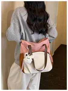 Vue de dos d’une personne portant un sac rose, écru et caramel avec un pendentif ourson en peluche