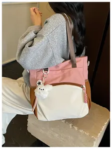 Vue portée d’un cabas rose, blanc et brun, avec poche zippée et pendentif lapin en peluche