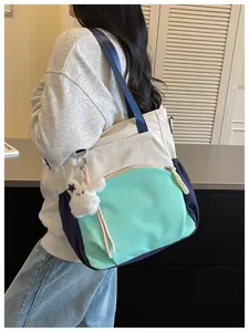Vue de côté d’une femme portant un sac crème et menthe, avec détails marine et un lapin en peluche