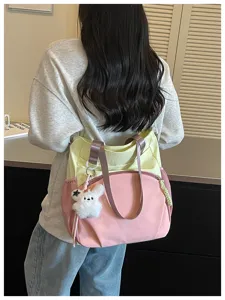 Vue arrière d’une femme portant un sac rose et jaune pâle, aux anses lilas et au porte-clés lapin