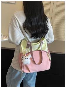Vue arrière d’un modèle portant un cabas rose et jaune pâle avec un pendentif lapin en peluche