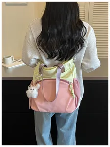 Vue de dos d’un sac en nylon rose et jaune pâle, avec anses violettes et un ourson en peluche