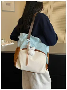 Vue de dos d’une femme portant un sac bleu, crème et brun avec un ourson en peluche