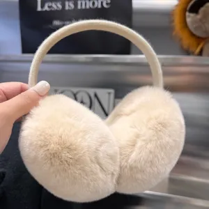 Close-up of cream plush earmuff cups with a soft elastic headband, held against a metal backdrop
