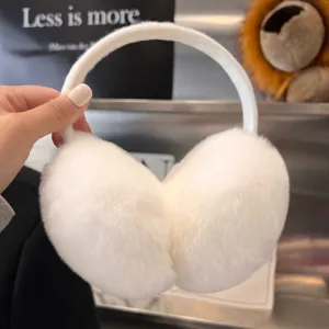 Hand-held view of fluffy white earmuffs, showing the curved headband and soft plush ear pads