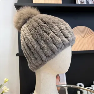 Close-up of a gray ribbed plush hat with a taupe fur pom-pom, displayed on a mannequin