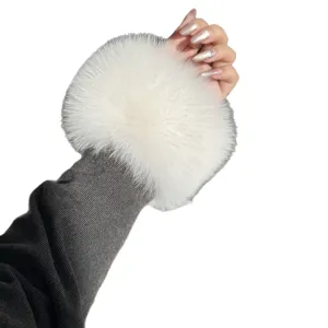 White fluffy fur wrist cuff shown against a sleeve, with a soft round shape and dense pile