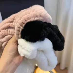 Close-up of pink, black and white plush pieces held by hand, showing their soft fur texture