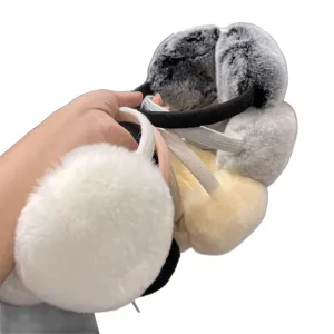 Plush winter earmuffs in gray, white and beige, held at an angle to show their soft padded cups