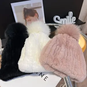 Three women's plush knit winter hats in black, white and pink, each topped with a fluffy pom-pom