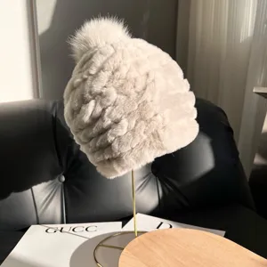 Detail showing pale gray braided fur texture and a fluffy pom-pom on a display stand