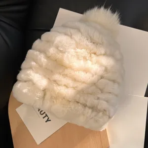 Close-up of a white plush knit hat, showing its soft ribbed texture and fluffy matching pom-pom