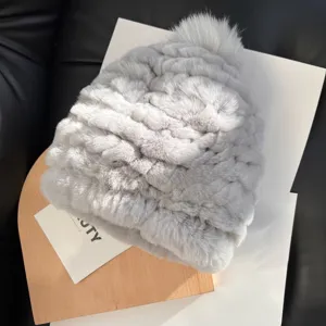 Close-up of a pale gray fluffy winter hat showing its layered knit texture and matching pom-pom