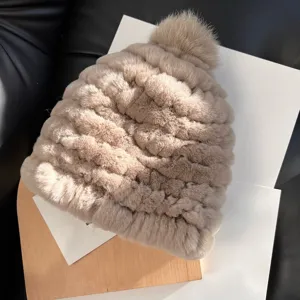 Close-up of the raised plush knit texture and matching pom-pom on a beige winter hat