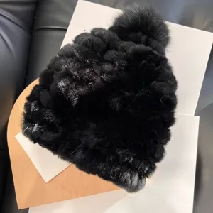Close-up of a black plush knitted hat showing its raised texture and matching fluffy pom-pom