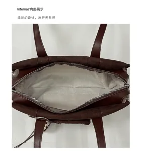 Top-down view of an open brown bag showing its beige-gray woven lining and zippered interior