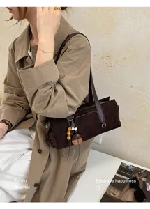 Shoulder-carried dark brown suede-texture bag with leather straps, zipper, and wooden charms