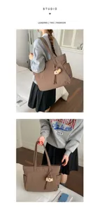 Sac cabas marron en nylon, poche latérale et charm ourson, porté à la main ou à l’épaule.