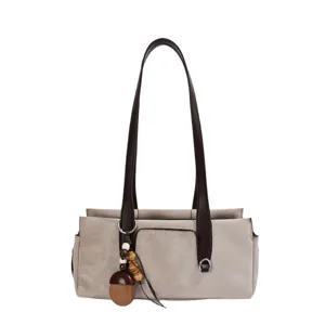 Light gray suede-look shoulder tote with dark brown handles, metal rings and a wooden charm