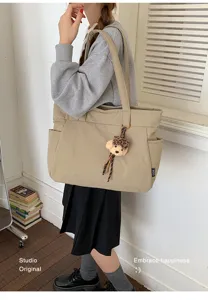 Femme portant un cabas beige en nylon, avec poches latérales et petit ourson à carreaux bruns