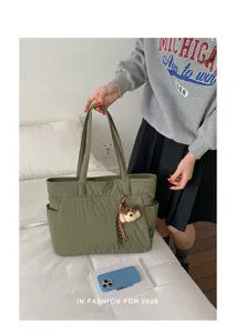 Cabas en nylon vert olive tenu, avec deux anses, poches latérales et ourson en peluche